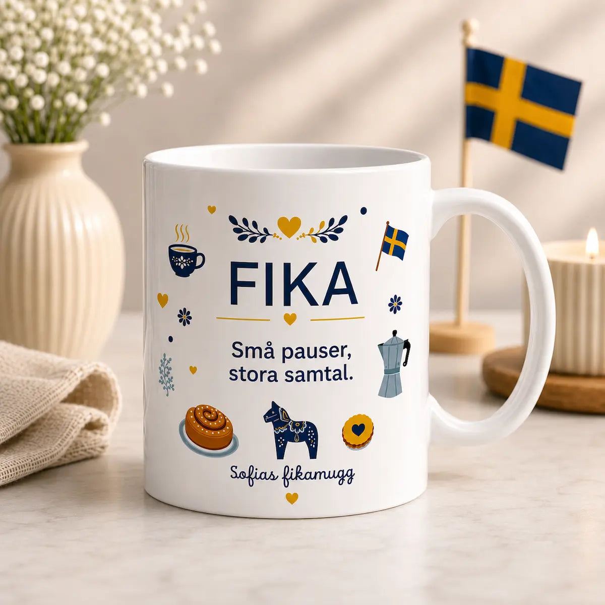 White mug with 'FIKA' text and illustrations on a table with decorative items.